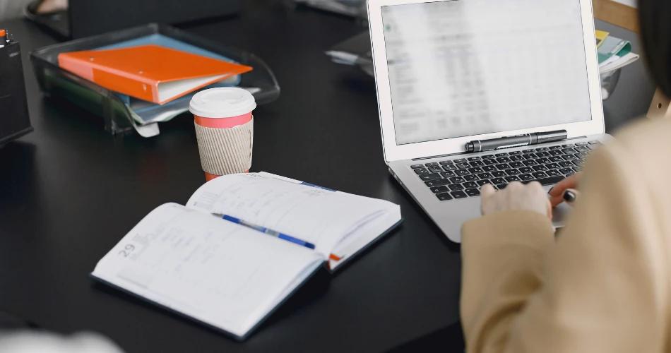 Student reviewing MHT CET 2025 objection results and answer key updates on laptop with study materials and notes on desk